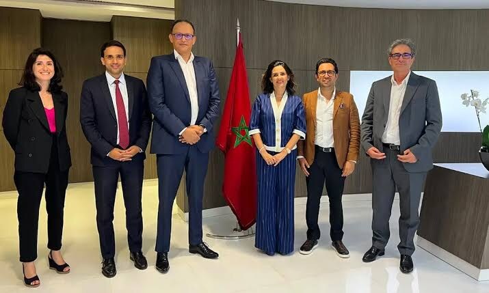 Lamia Tazi with colleagues at an institutional meeting beside the Moroccan flag