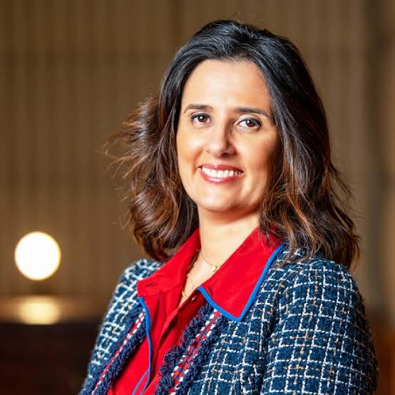 Lamia Tazi photographed in a warm interior setting, wearing a structured jacket
